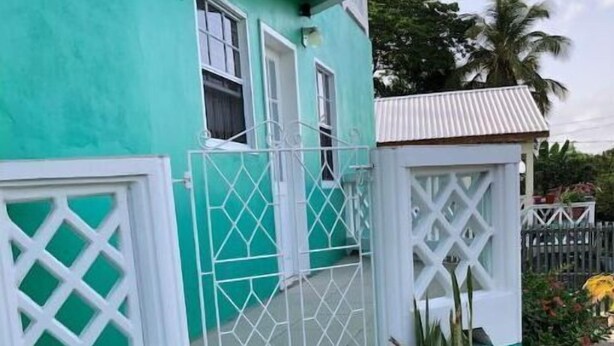 A house with a green exterior, white lattice windows, and a small porch with steps.