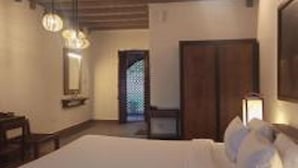 A bedroom with a large bed, wooden beams on the ceiling, a mirror, and a door with a patterned design. - Mango Hill Yercaud (Yercaud)