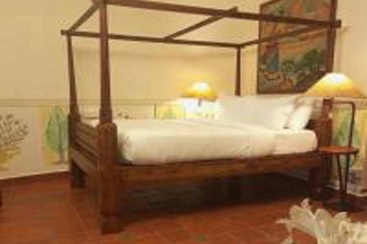 Ein Himmelbett mit Holzrahmen und weißer Bettwäsche.