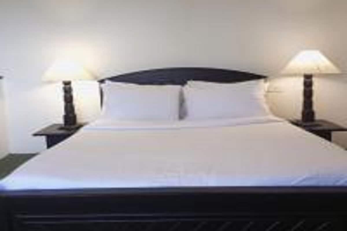 Ein Standard-Hotelzimmer mit einem Einzelbett, zwei Nachttischen und zwei Wandlampen.