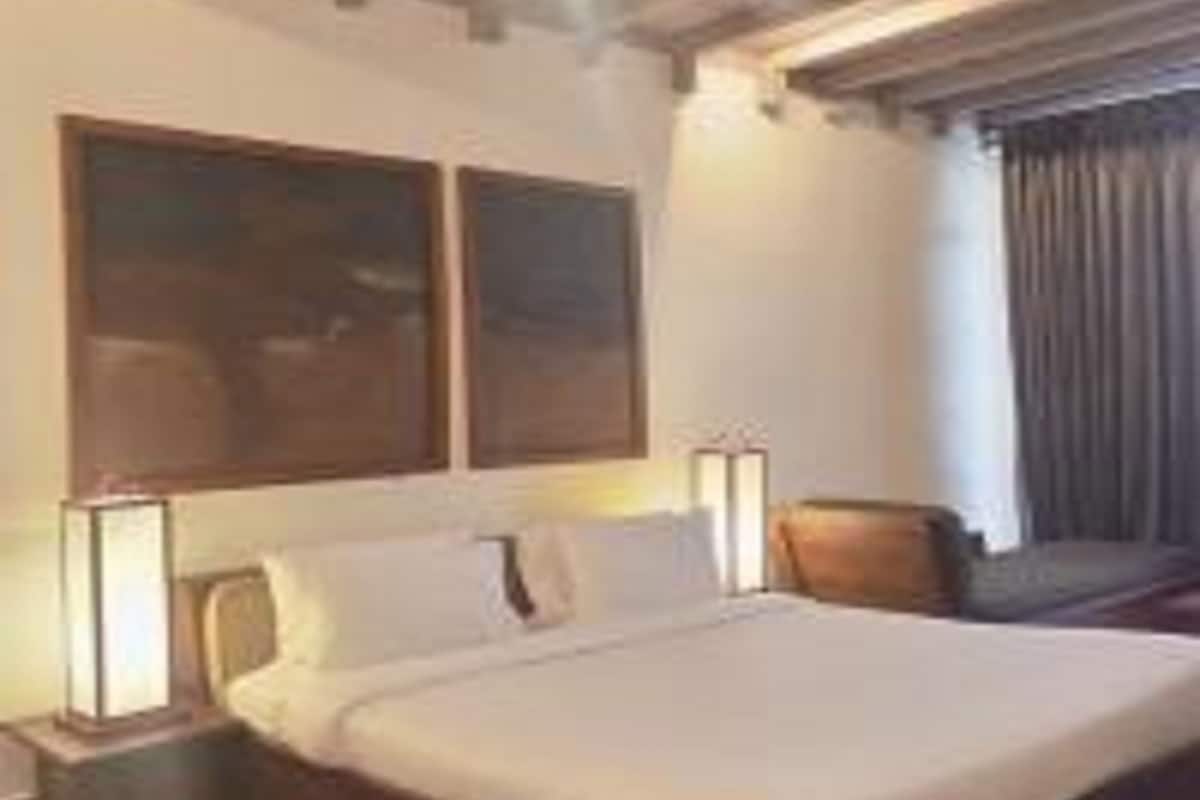 Ein Hotelzimmer mit einem großen Bett, zwei Nachttischen und einem Fenster mit Vorhängen.