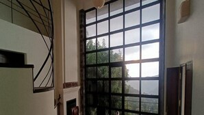 A room with a large window, a fireplace, and a staircase. - Mango Hill Yercaud (Yercaud)