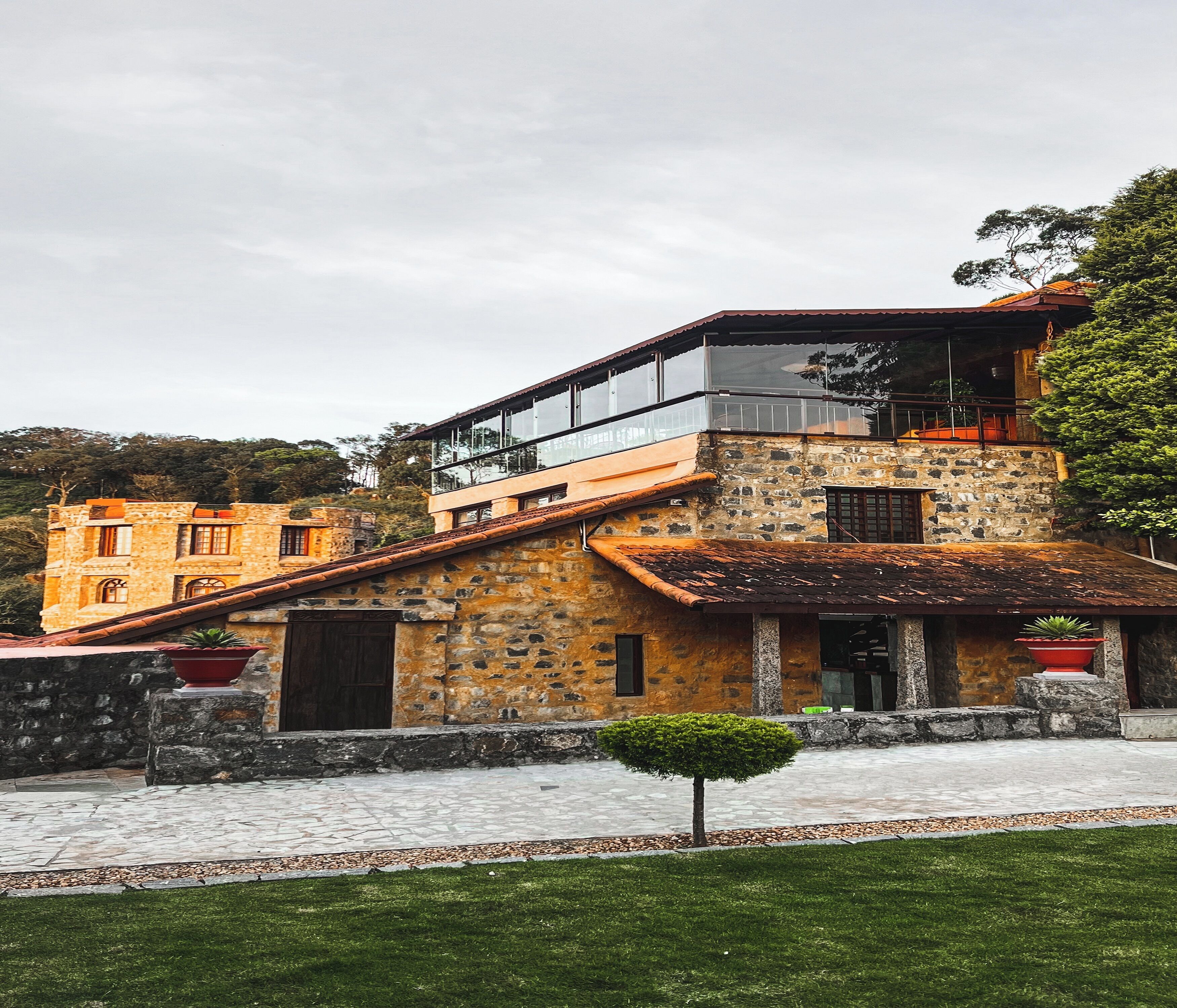 A multi-story stone building with a mix of traditional and modern architectural elements, including a balcony and a glass enclosure.