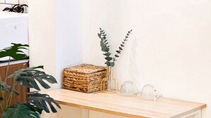 A small wooden table with two stools, a potted plant, a woven basket, and a vase with a plant. - Cozy Modern Place with Projector @ Near Pink Church (Thành phố Hồ Chí Minh)