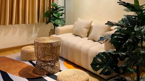 A modern living room with a sofa, two abstract paintings, a floor lamp, and large green plants. - Cozy Modern Place with Projector @ Near Pink Church (Thành phố Hồ Chí Minh)