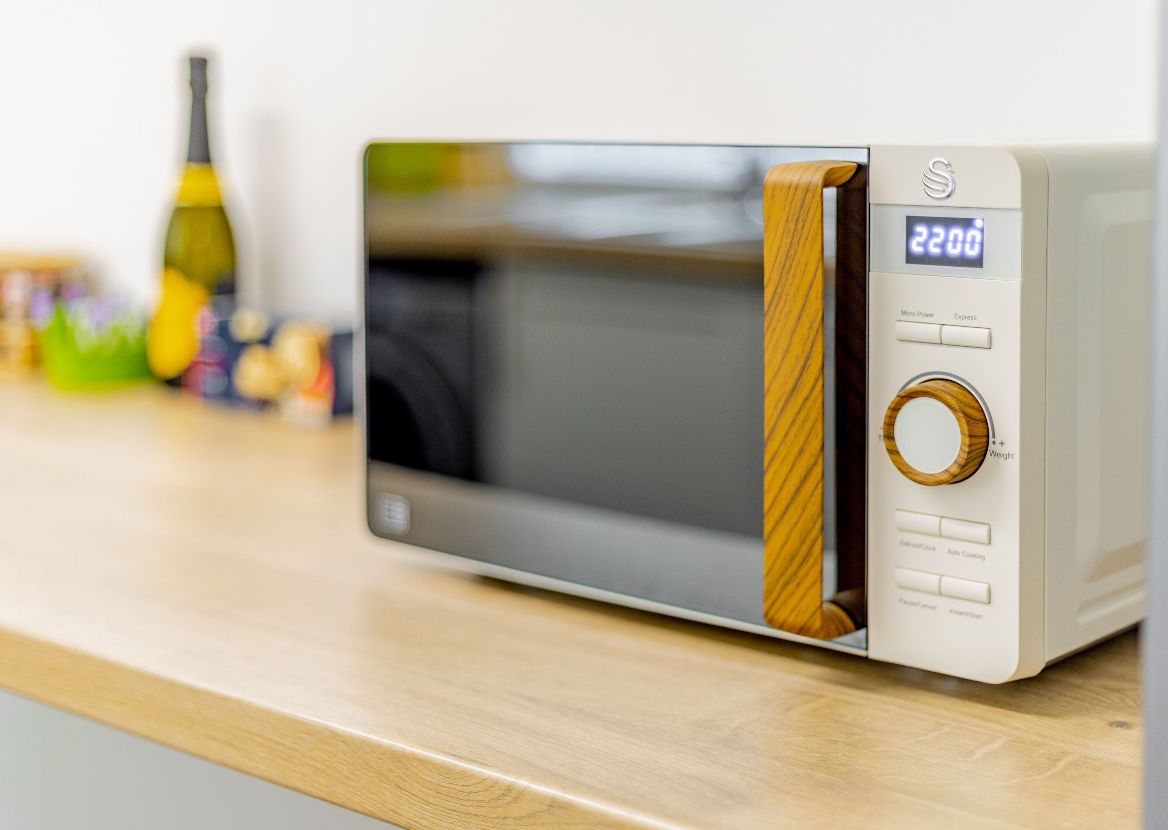 A microwave oven with a wooden panel design, a digital display showing 2200, and a weight adjustment knob.