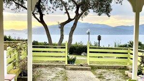 An outdoor patio with a view of a lake and mountains, a yellow fence, and a pathway leading to a gate. - Les Bouganvilles by SolturElba (Capoliveri)