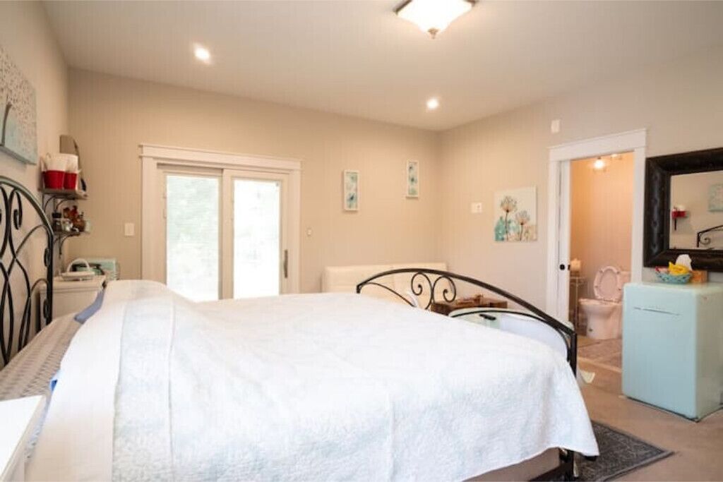 Un dormitorio con cama, cómoda, espejo y puerta que da a un baño.