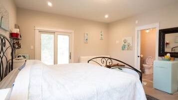 Un dormitorio con cama, cómoda, espejo y puerta que da a un baño.