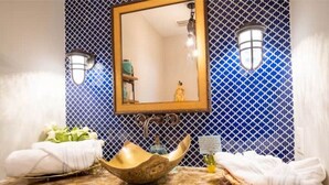 Une salle de bain avec un plan de toilette en pierre, un lavabo en bois et un miroir.