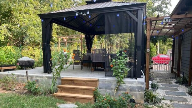 Un patio abrité avec un banc en bois, une table et des chaises.
