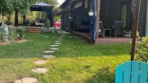 Un patio couvert avec une terrasse en bois, des dalles de pierre servant de marchepied et du mobilier d’extérieur.