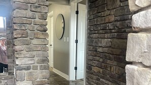 Een interieur met stenen muren, een stenen aanrecht en gootsteen, een deur naar een andere kamer en een stenen trap.