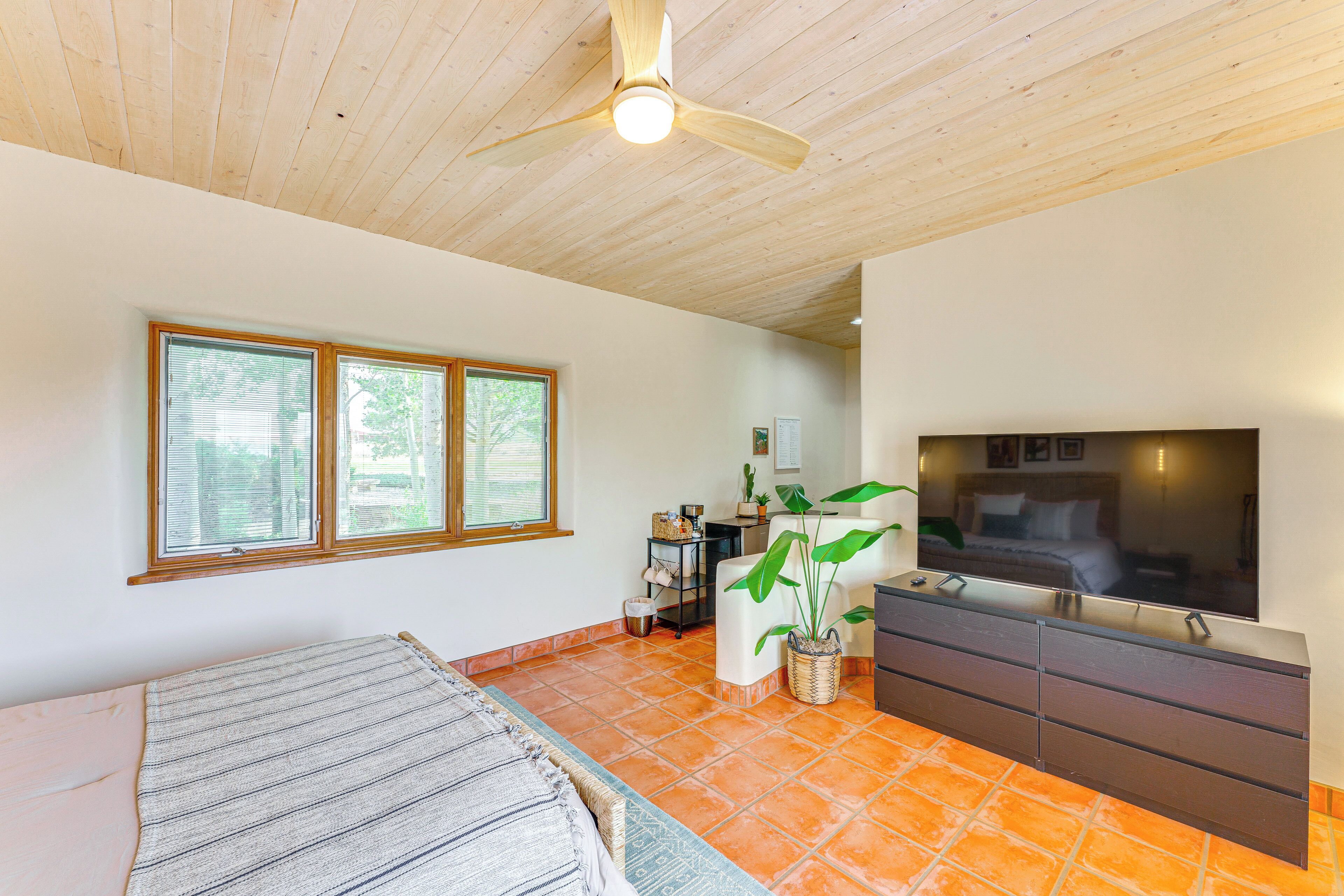 A bedroom with a bed, a dresser, a TV, and a ceiling fan.