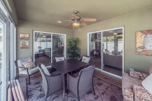 A patio area with a table and chairs, a ceiling fan, and a sliding glass door leading to an outdoor space.