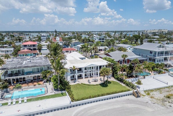 A coastal residential area with multiple houses, a swimming pool, and a clear view of the ocean.