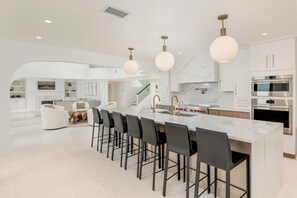 A modern kitchen with a central island, stainless steel appliances, and a dining area with bar stools.