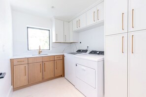 A modern kitchen with white cabinetry, a sink, and a washing machine.