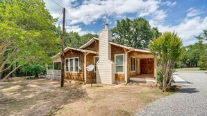 A two-story log cabin with a chimney, large windows, and a porch. - Pottboro Vacation Rental w/ Private Hot Tub! (Pottsboro)