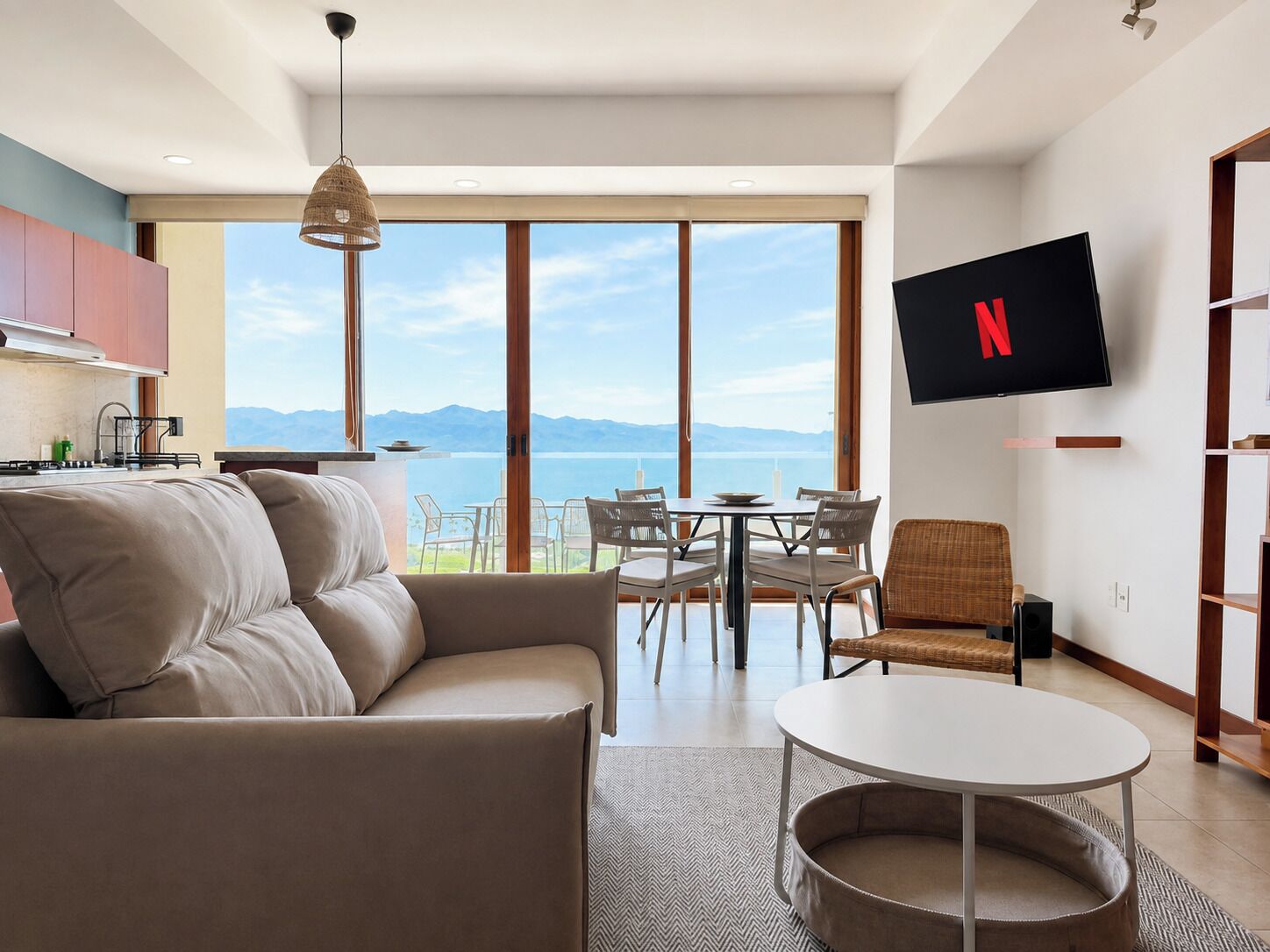 A modern living room with a sofa, a round table, and a flat-screen TV mounted on the wall.