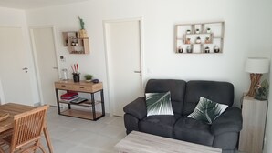 En moderne stue med en mørkegrå sofa, et træbord og en reol med pynteting.