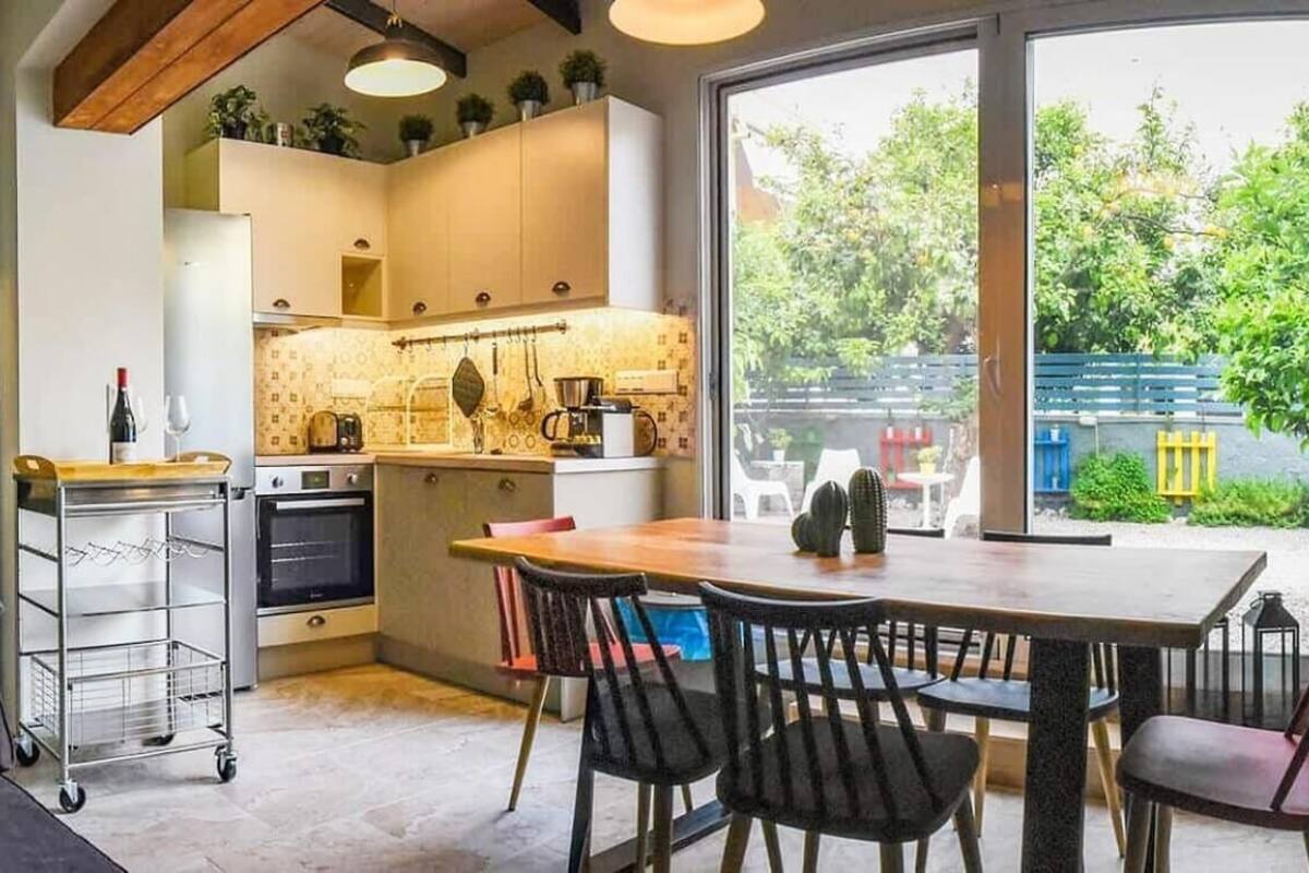 Un salon confortable avec un canapé, un coin repas avec une table et des chaises, une cuisine équipée d’appareils modernes et une grande fenêtre donnant sur l’extérieur.