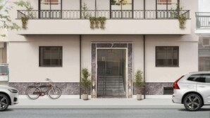 Un bâtiment moderne avec une entrée numérotée 7, un vélo garé à l’extérieur et deux plantes en pot sur le trottoir.