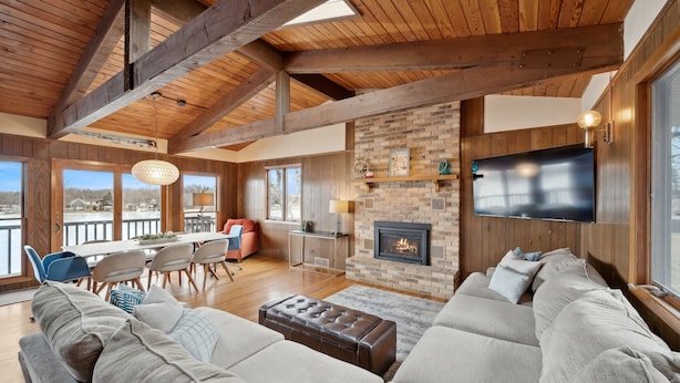 A spacious living room with a large sofa, a fireplace, and a television. - Cedar Lake getaway - sauna, paddle boards & raft! (Annandale)
