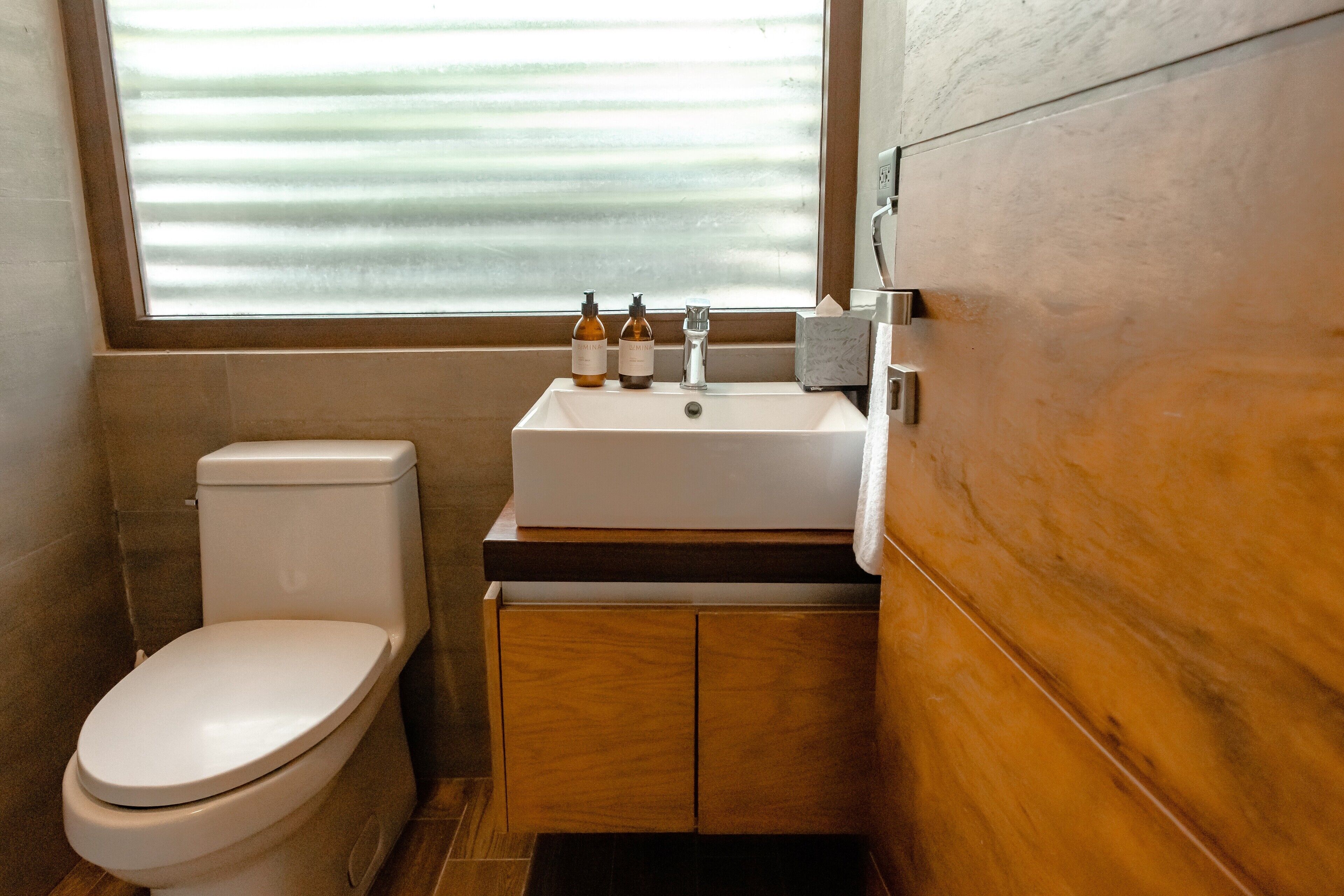 A small bathroom with a toilet, a sink, and a window.