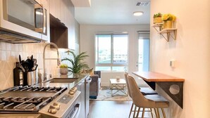 Een moderne keuken met een gasfornuis, magnetron en een eethoek met barstoelen.