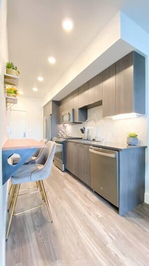 A modern kitchen with a central island, built-in appliances, and a dining area with a bar stool.
