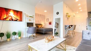 Een moderne woonkamer met een open haard, een bank, een eettafel en een televisie.