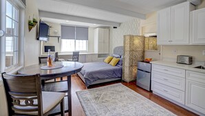 A compact bedroom with a bed, bedside table, and a small desk area. - Remodeled Studio w/Fast Wi-Fi in Heart of Bay Area (Milpitas)