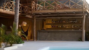 Un espace aménagé au bord de la piscine, comprenant un bar, un hamac et une structure en béton.