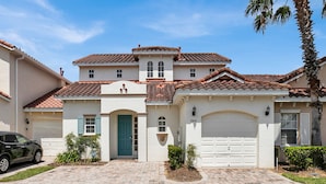 A two-story house with a red-tiled roof, a blue front door, and a garage.