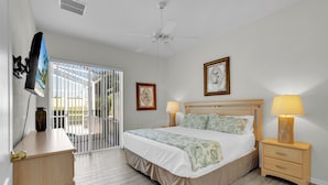 A bedroom with a bed, bedside lamps, a TV mounted on the wall, and a ceiling fan.