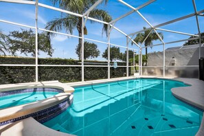 Ein klarer, überdachter Pool mit gefliestem Rand, umgeben von einem weißen Metallrahmen und im Hintergrund Palmen.