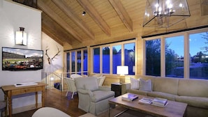 Amplia sala de estar con techo de madera, ventanas grandes, un sofá, una mesa de centro y un sillón.