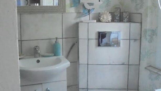 Un baño pequeño con lavamanos, espejo, inodoro y una escoba.