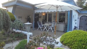 A house with a patio area featuring a table and chairs, a decorative lamp, and a covered seating area. - Small oasis of peace surrounded by greenery - 3 minutes from Kromlau Rhododendron Park (Gablenz)