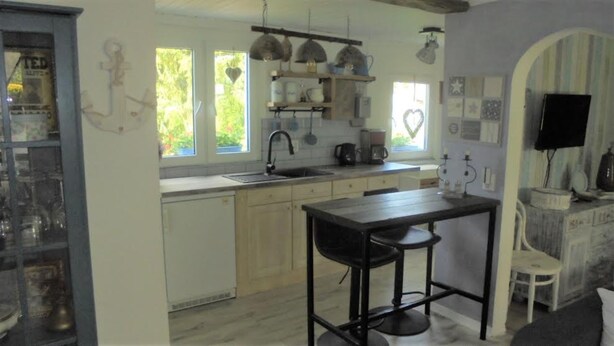 A compact kitchen with a sink, stove, and hanging lights. There is a small dining area with a table and two stools. - Small oasis of peace surrounded by greenery - 3 minutes from Kromlau Rhododendron Park (Gablenz)