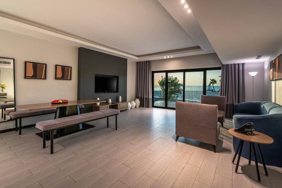 Una sala de estar moderna con televisor grande, comedor y vista al océano.