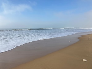 A sandy beach with gentle waves and a clear sky.