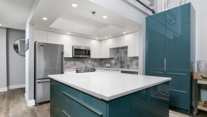 Una cocina moderna con una isla central, electrodomésticos de acero inoxidable y armarios color turquesa.
