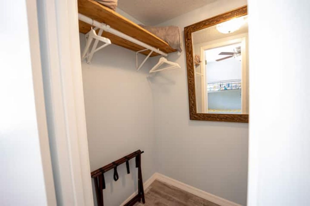 Un couloir étroit avec une étagère en bois, un miroir et un porte-manteau.
