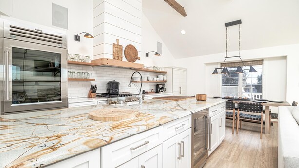 Een moderne keuken met witte kasten, een marmeren aanrechtblad en een inbouwoven.