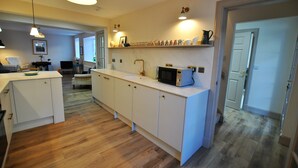 A modern kitchen with white cabinetry, a microwave, and pendant lighting. - Sea Holly Cottage- coastal retreat Pittenweem (Pittenweem)