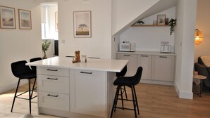 Een moderne keuken met witte kasten, een centraal eiland met barkrukken en hanglampen.