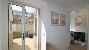Een modern interieur met een houten trap, een glazen deur naar een buitenruimte, en twee ingelijste foto's aan de muur.