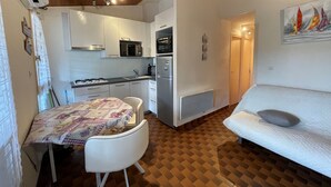 A compact living space with a kitchenette, a dining area with a table and chairs, and a sofa.